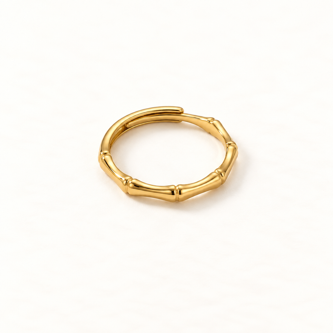 A gold bamboo ring with segmented stalk design and natural node details, open adjustable band mimicking organic bamboo sections, shown from front and side angles on a clean white background displaying the botanical texture, Asian-inspired natural form, and polished gold finish.