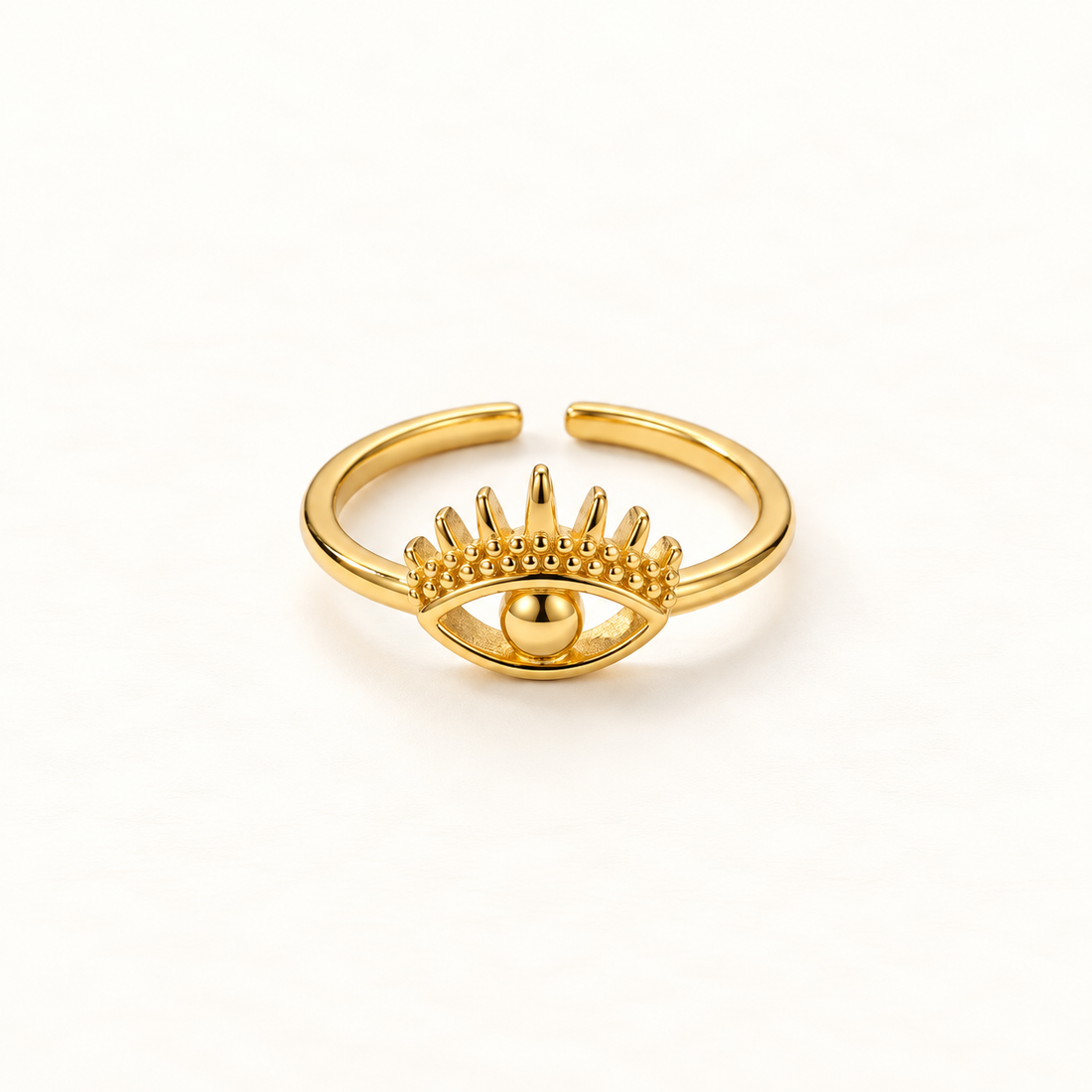 A gold evil eye ring with detailed eyelashes, curved brow, and central spherical pupil, open adjustable band, shown from front and side angles on a clean white background displaying the protective symbol design, intricate lash detail, and polished gold finish.