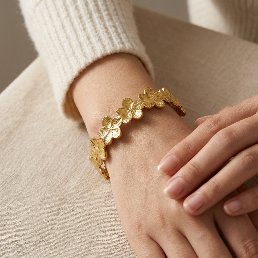 Close-up of a feminine wrist wearing a gold forget-me-not flower chain bracelet with delicate linked floral charms, the dainty blossoms wrapping around the wrist. Soft natural lighting, warm beige linen background, natural skin texture with visible pores and slight imperfections.