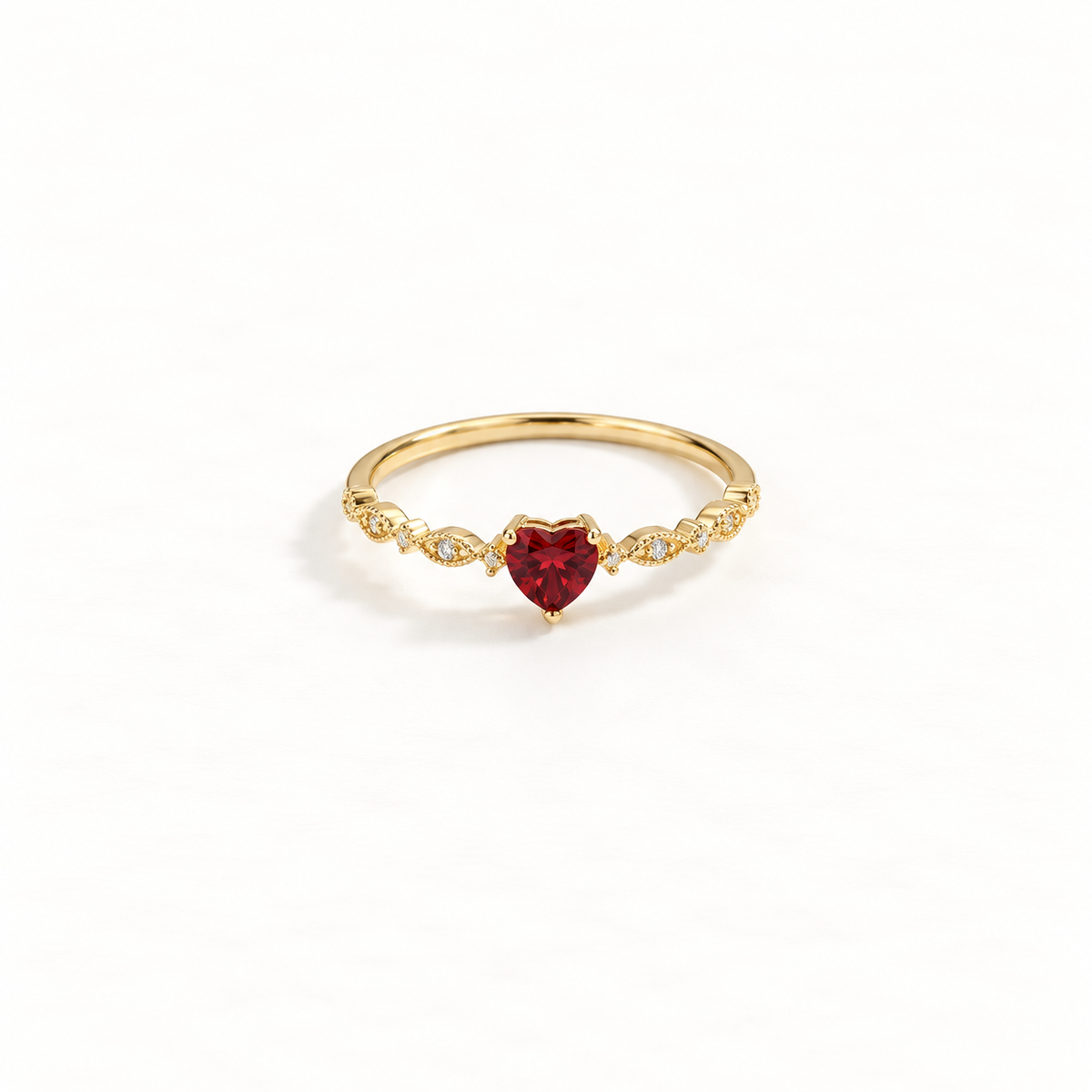 A gold heart ring with deep red ruby center stone and clear crystal accents on delicate band, romantic design with faceted gemstone, open adjustable band, shown from front and side angles on a clean white background displaying the passionate red hue, sparkling stone setting, and polished gold finish.