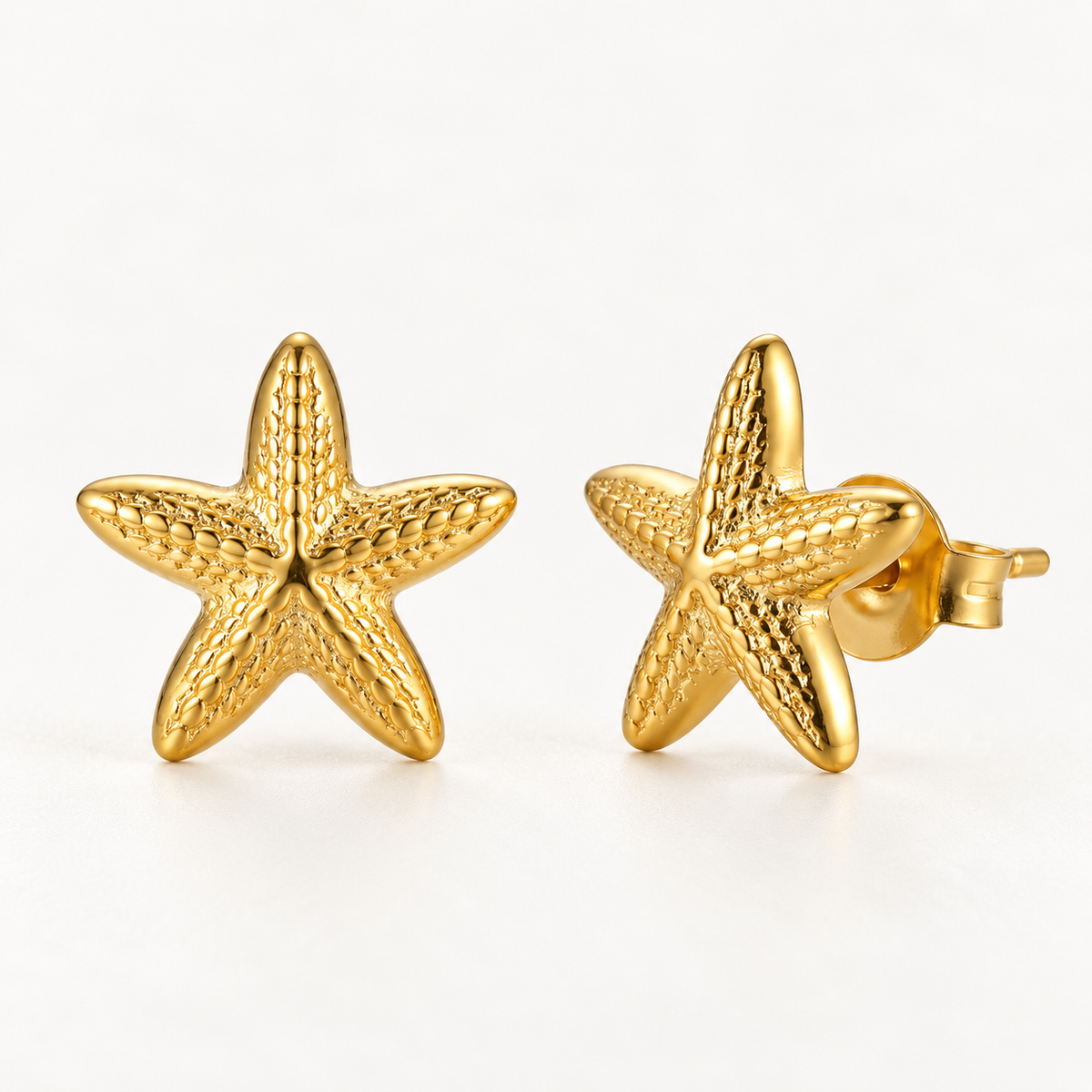 A pair of 18k gold starfish-shaped stud earrings with textured surface detail and five points, shown from front and side angles on a clean white background displaying the organic sea-inspired texture and post with butterfly backing.