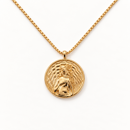 A gold Aphrodite love coin necklace with detailed medallion pendant depicting goddess of beauty with flowing hair and dove, ornate border with heart motifs, box chain design, shown from front and side angles on a clean white background displaying the intricate love symbolism, classical figural relief, and polished gold finish.