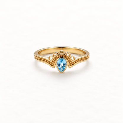 A gold aquamarine teardrop ring with pear-shaped blue stone in vintage-inspired milgrain setting, delicate beaded band detail and scalloped edges, open adjustable design, shown from front and side angles on a clean white background displaying the soft blue hue, intricate metalwork, and polished gold finish.