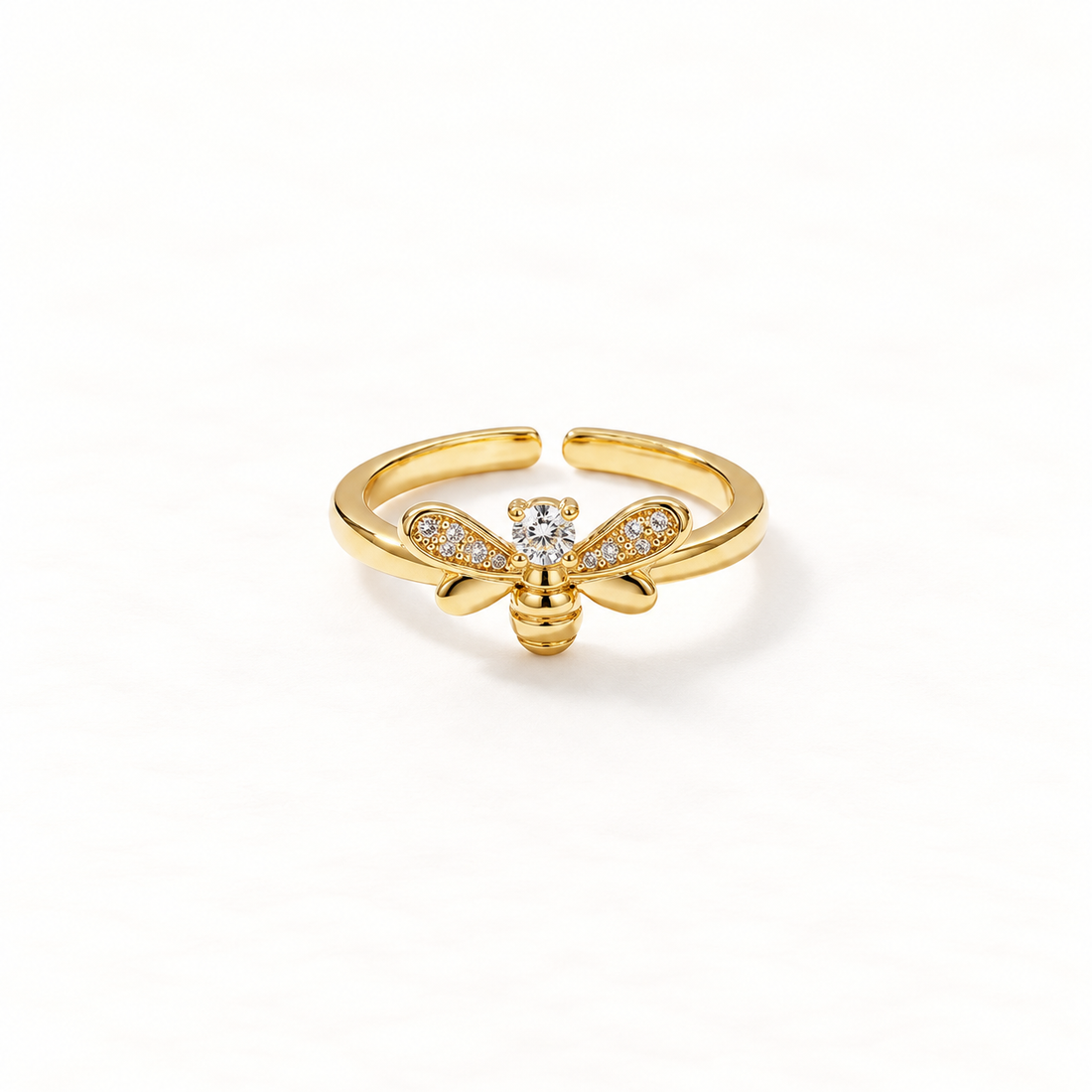 A gold bee ring with detailed insect body, pave crystal wings and body segments, delicate open adjustable band, shown from front and side angles on a clean white background displaying the intricate nature-inspired design, sparkling stone detail, and polished gold finish.
