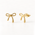 A pair of 18k gold bow stud earrings on a clean white background, one facing forward showing the delicate ribbon bow detail, the other angled to display the post and butterfly backing.