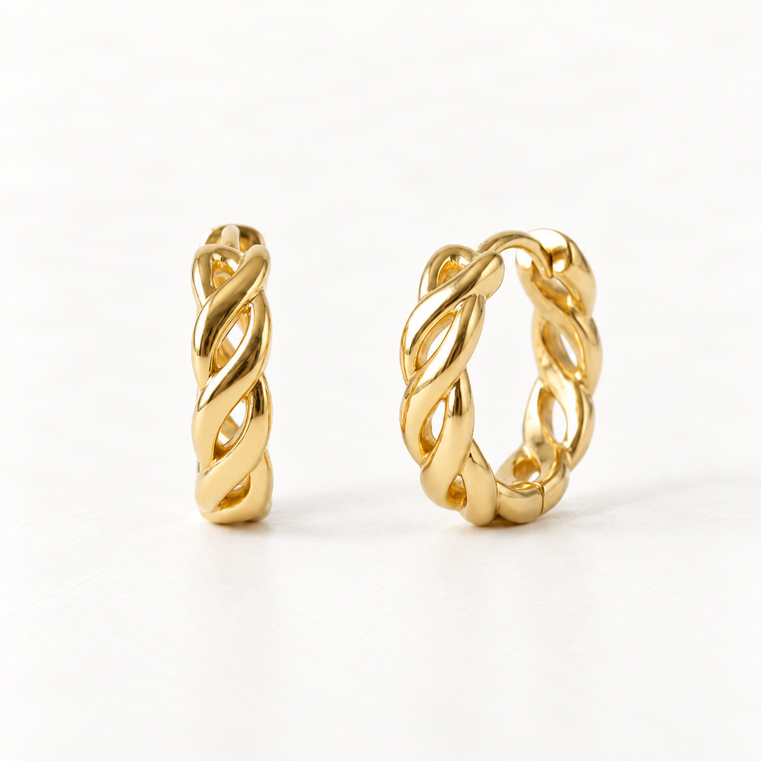 A pair of 18k gold braided twist huggie hoop earrings with intricate woven open pattern, shown from front and side angles on a clean white background displaying the detailed interlaced texture and hinged closure.