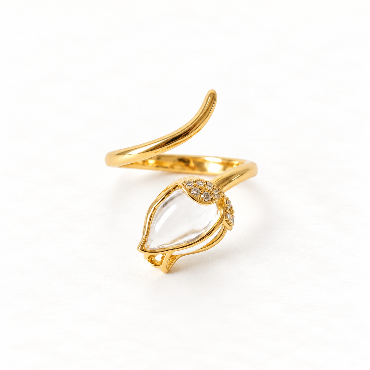 A gold clear crystal teardrop ring with marquise-shaped clear quartz stone in delicate prong setting, small accent stones on band, open adjustable design, shown from front and side angles on a clean white background displaying the transparent clarity, elegant minimal setting, and polished gold finish.