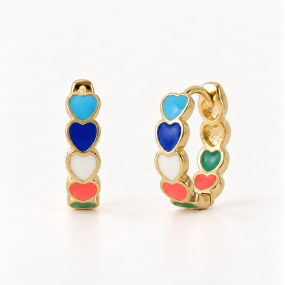 A pair of 18k gold huggie hoop earrings with multi-colored enamel hearts in blue, navy, white, coral, and green, shown from front and side angles on a clean white background displaying the vibrant glossy enamel detail and hinged closure.