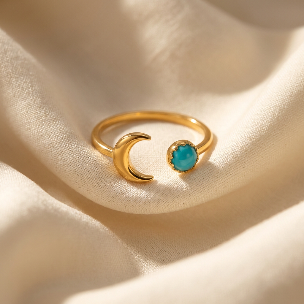 A gold crescent moon turquoise ring with curved moon silhouette and round vibrant turquoise stone lying flat on a white background with soft natural shadows, showing the bright blue-green hue, lunar symbolism, and polished gold finish from above.