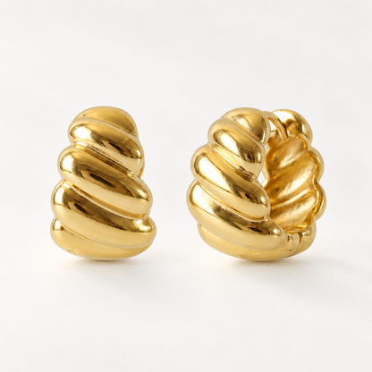 A pair of 18k gold croissant-shaped huggie hoop earrings with twisted rope texture, shown from front and side angles on a clean white background displaying the sculptural ridges and hinged closure.