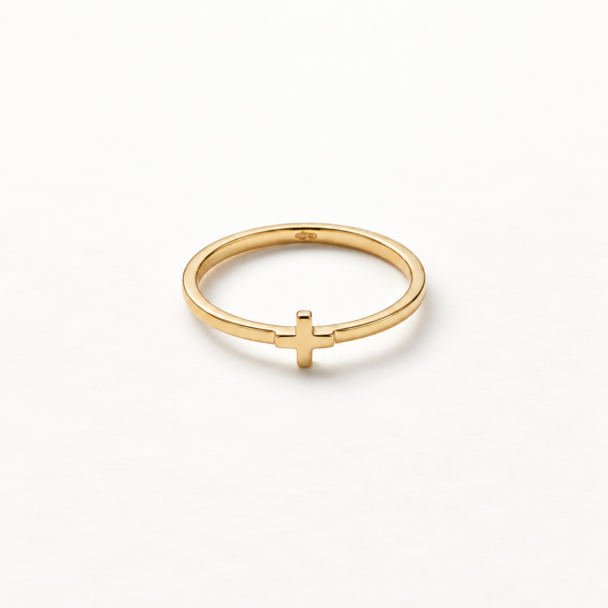 A gold cross ring with simple thin band and small centered cross symbol, delicate religious design with smooth polished surface, shown from front and side angles on a clean white background displaying the minimal spiritual symbolism, sleek band, and polished gold finish.