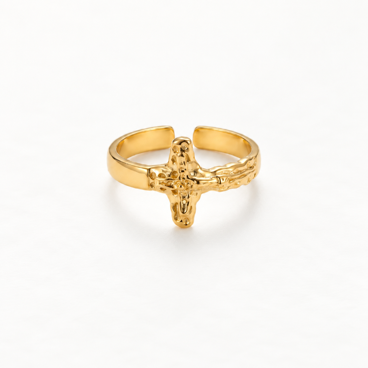 A gold crucifix cross ring with detailed textured 3D cross design and organic hammered band, open adjustable religious statement piece, shown from front and side angles on a clean white background displaying the sculptural crucifix form, intricate surface texture, and polished gold finish.