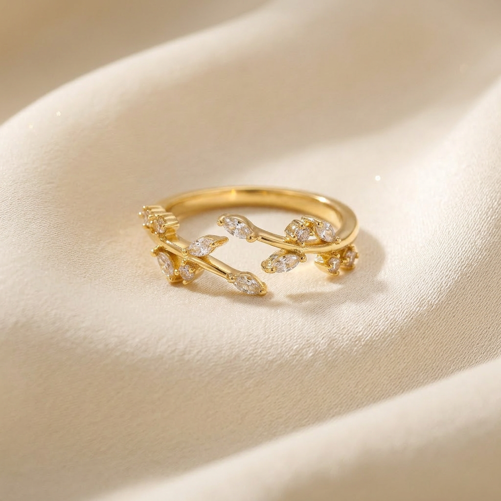 A gold crystal vine ring with winding branch design and clear pave stones set in leaf-shaped settings lying flat on a white background with soft natural shadows, showing the nature-inspired sparkle, intricate twig texture, and polished gold finish from above.