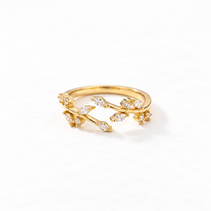 A gold crystal vine ring with winding branch design and clear pave stones set in leaf-shaped settings, delicate botanical open band, shown from front and side angles on a clean white background displaying the nature-inspired sparkle, intricate twig texture, and polished gold finish.