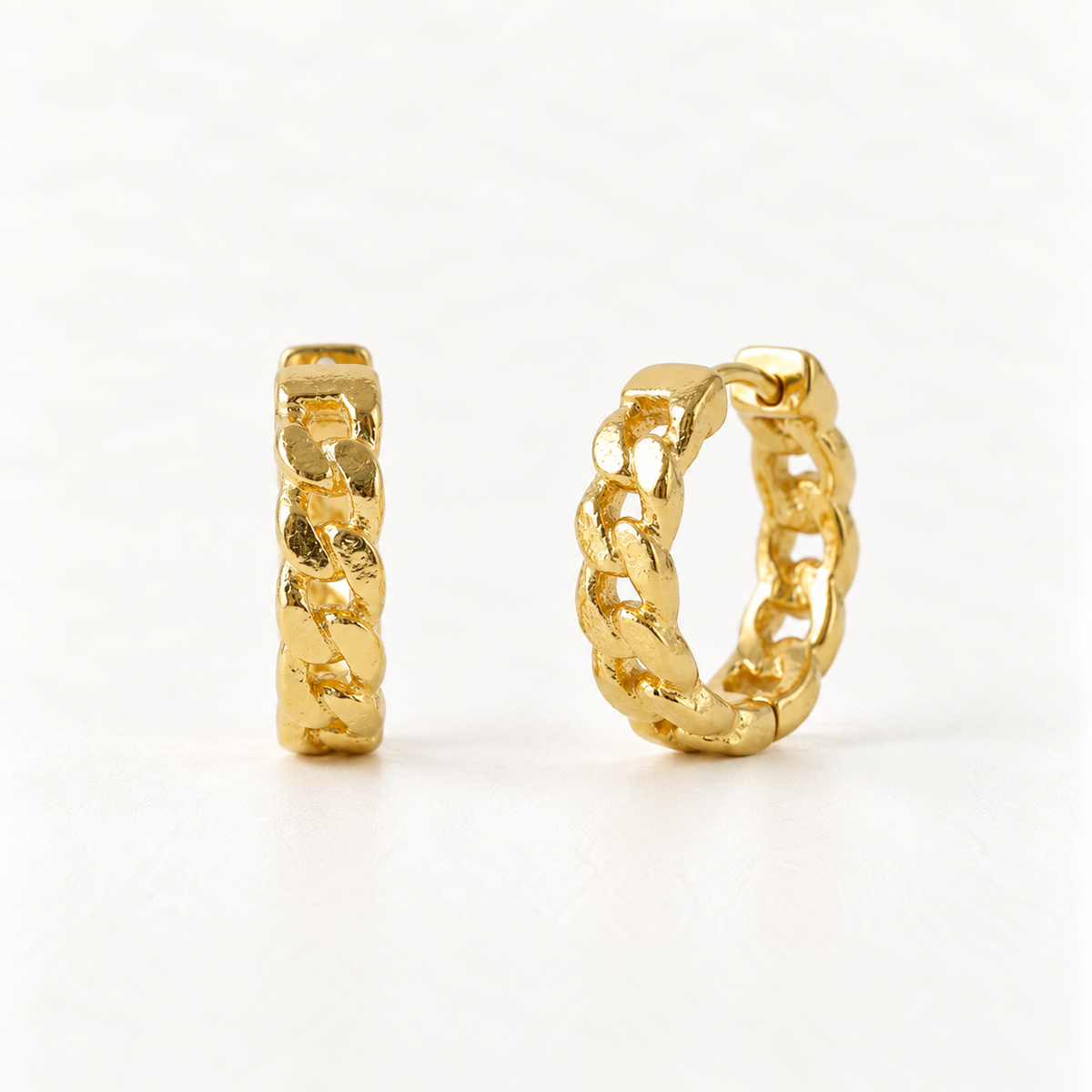 A pair of 18k gold cuban link chain huggie hoop earrings with interlocking oval link pattern, shown from front and side angles on a clean white background displaying the detailed chunky chain texture and hinged closure.