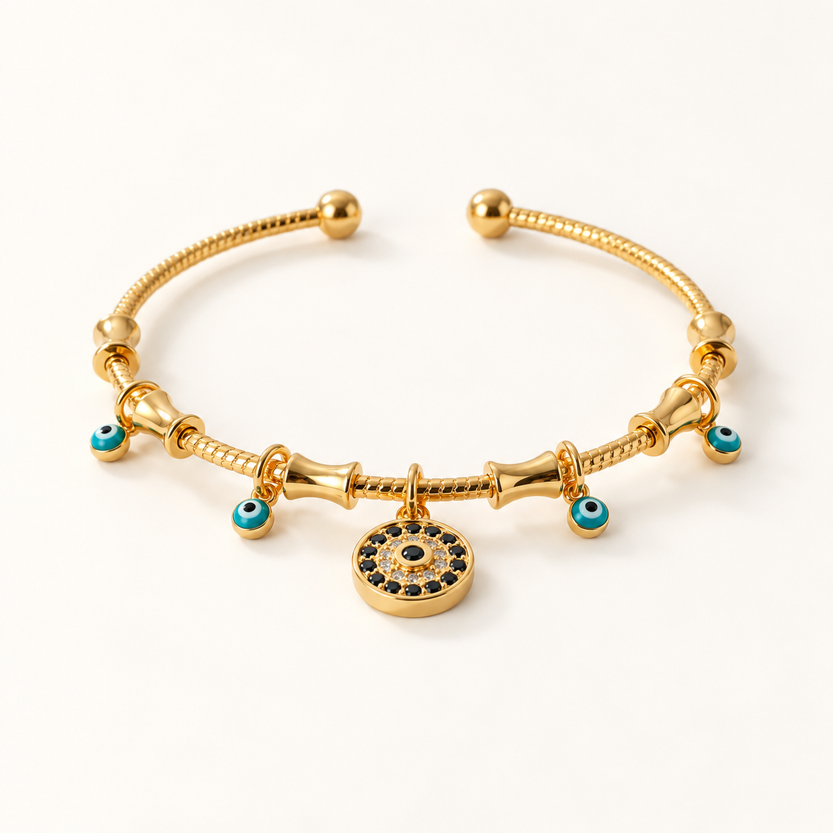 A gold evil eye charm bracelet with coiled snake chain design, central circular evil eye pendant with blue stones, and smaller evil eye bead accents, shown from front and side angles on a clean white background displaying the protective charm details and adjustable ball ends.