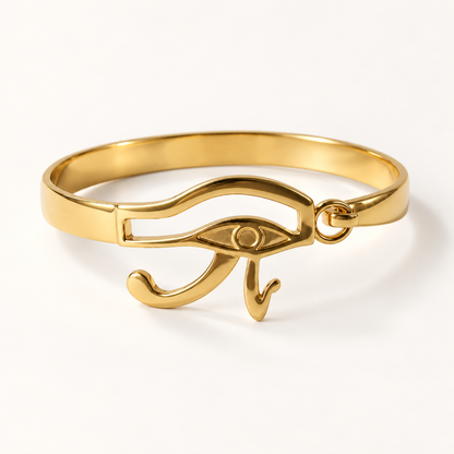 A gold Eye of Horus bracelet with detailed Egyptian symbol centerpiece, open cuff design with curved tail accent, shown from front and side angles on a clean white background displaying the protective eye detail, hieroglyphic styling, and polished gold finish.
