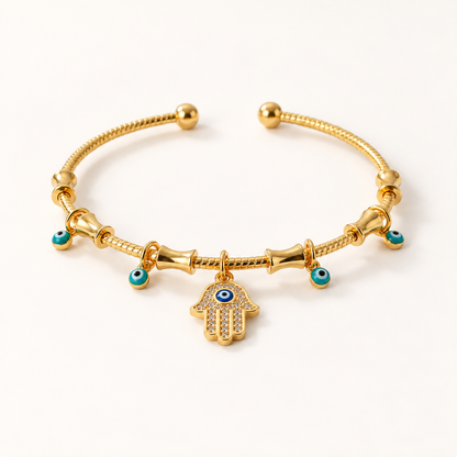 A gold Hamsa hand bracelet with turquoise blue beads and central Hamsa charm featuring evil eye detail, shown from front and side angles on a clean white background displaying the delicate chain links, adjustable ball ends, and spiritual charm design.