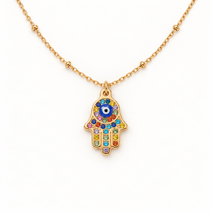 A gold Hamsa hand pave necklace with colorful crystal-encrusted palm, blue evil eye center, and rainbow stones on fingers, protective amulet design on delicate chain, shown from front and side angles on a clean white background displaying the vibrant multicolor sparkle, intricate hand detail, and polished gold finish.