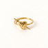 A gold heart and sword ring with detailed anatomical heart pierced by a dagger, open adjustable band, shown from front and side angles on a clean white background displaying the romantic yet edgy symbolism, intricate heart texture and blade detail, and polished gold finish.