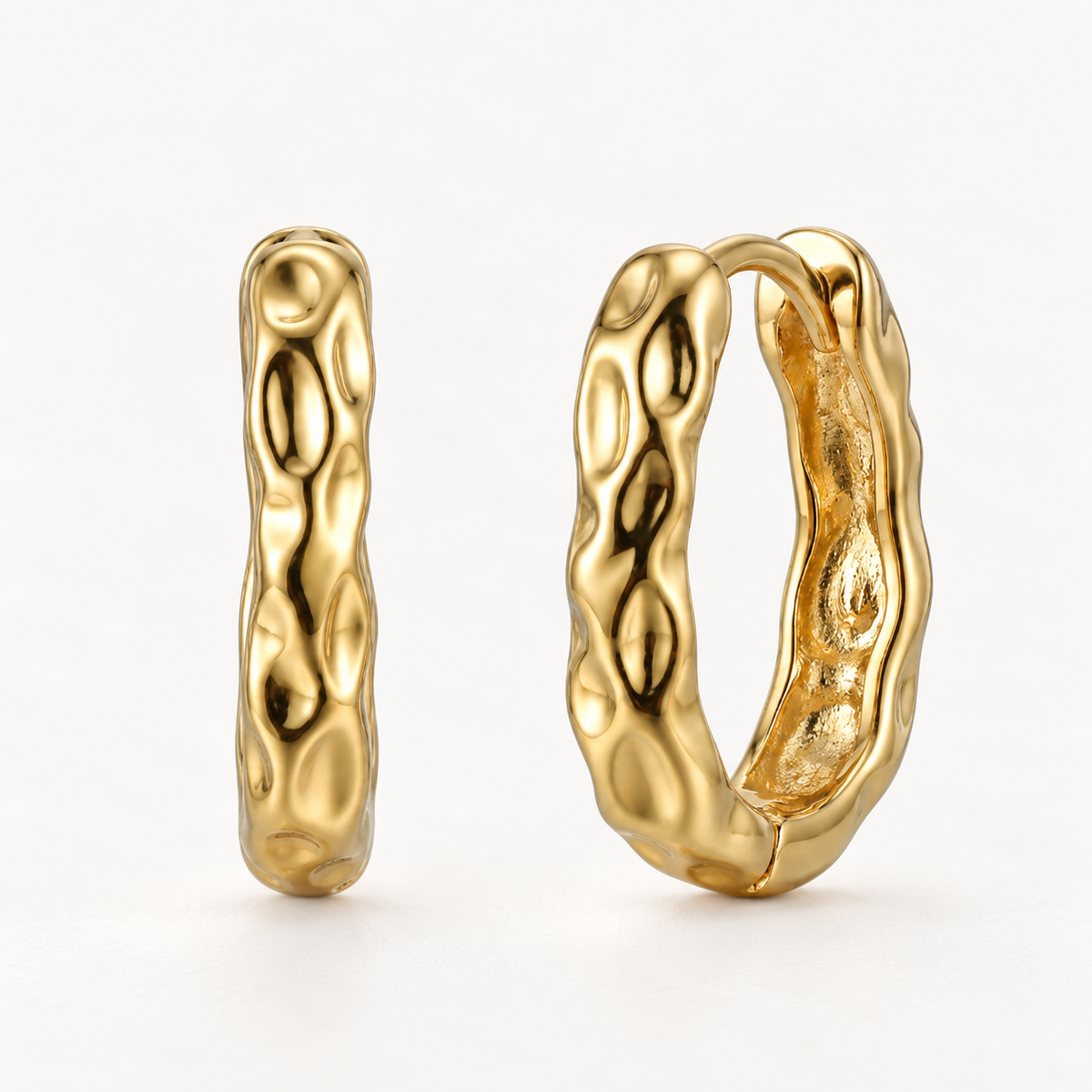 A pair of 18k gold lava-textured huggie hoop earrings with organic bumpy molten surface, shown from front and side angles on a clean white background displaying the irregular bubble-like detail and hinged closure.