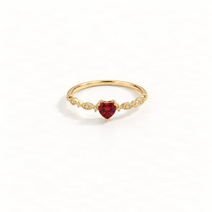 A gold heart ring with deep red ruby center stone and clear crystal accents on delicate band, romantic design with faceted gemstone, open adjustable band, shown from front and side angles on a clean white background displaying the passionate red hue, sparkling stone setting, and polished gold finish.