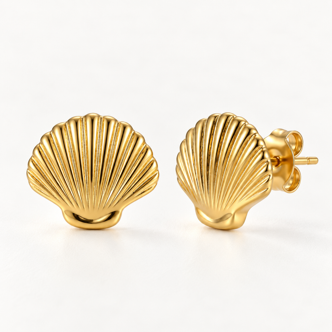 A pair of 18k gold scallop shell-shaped stud earrings with detailed ridged texture, shown from front and side angles on a clean white background displaying the organic sea-inspired grooves and post with butterfly backing.