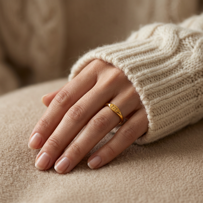 Close-up of a feminine hand wearing a gold angel number ring with "777" engraved on the band, the spiritual luck symbol visible on the finger. Soft natural lighting, warm beige linen background, natural skin texture with visible pores and slight imperfections.