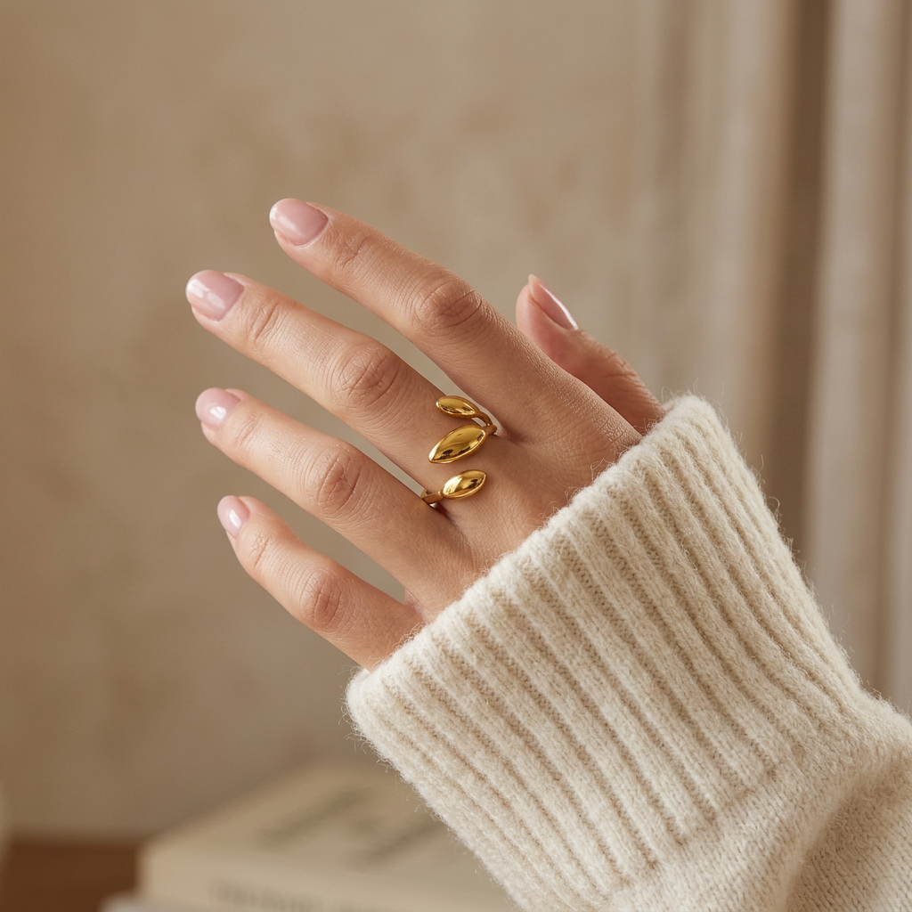 Close-up of a feminine hand wearing a gold sprout leaf ring with three oval botanical leaves, the organic plant-inspired design resting on the finger. Soft natural lighting, warm beige linen background, natural skin texture with visible pores and slight imperfections.