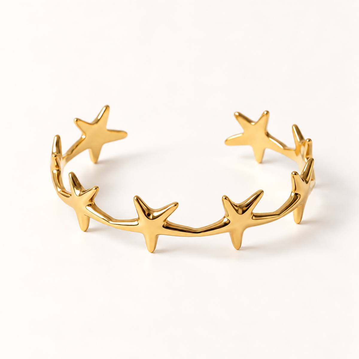 A gold star cuff bracelet with multiple five-point stars forming an open celestial band, shown from front and side angles on a clean white background displaying the polished star shapes, open cuff design, and cosmic constellation aesthetic.