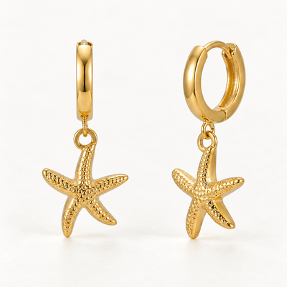 A pair of 18k gold huggie hoop earrings with dangling textured starfish charms, shown from front and side angles on a clean white background displaying the hinged closure and detailed five-point sea-inspired charm.