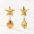 A pair of 18k gold starfish stud earrings with white pearl centers and dangling scallop shell charms, shown from front and side angles on a clean white background displaying the textured sea-inspired details and post with butterfly backing.