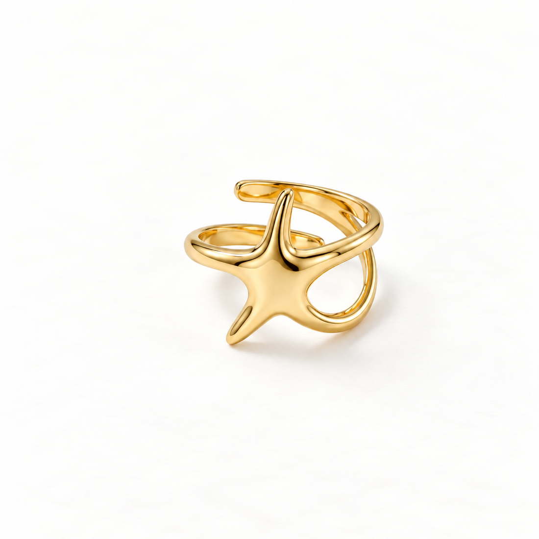 A gold starfish ring with five-pointed sea star shape and textured surface detail, open adjustable band with organic marine form, shown from front and side angles on a clean white background displaying the nautical beach aesthetic, intricate star texture, and polished gold finish.