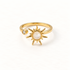 A gold sun spinner ring with rotating sunburst center, pearlescent moonstone center and small clear crystal accent, open adjustable band, shown from front and side angles on a clean white background displaying the kinetic celestial design, radiating rays, and polished gold finish.