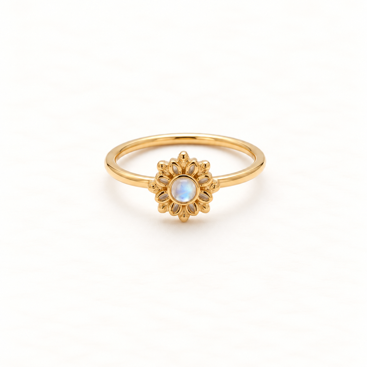 A gold sunburst flower ring with radiating petal design and central iridescent moonstone, delicate slim band, shown from front and side angles on a clean white background displaying the celestial bloom symbolism, detailed petal texture, and polished gold finish.