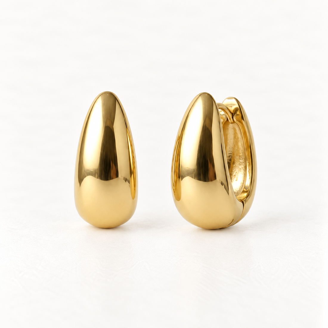 A pair of 18k gold teardrop dome huggie hoop earrings with sleek polished elongated profile, shown from front and side angles on a clean white background displaying the smooth reflective surface and hinged closure.