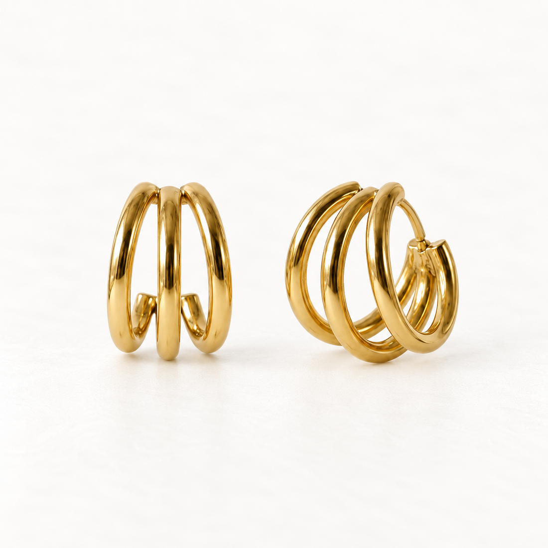 A pair of 18k gold triple band huggie hoop earrings with three parallel polished bands creating a stacked layered look, shown from front and side angles on a clean white background displaying the sculptural multi-band detail and hinged closure.