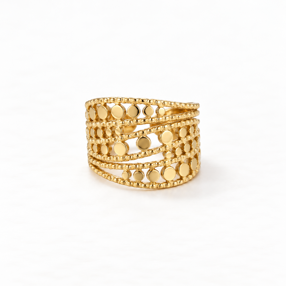 A gold wide band cutout ring with multiple rows of circular geometric cutouts and beaded edge details, openwork statement design, open adjustable band, shown from front and side angles on a clean white background displaying the intricate lattice pattern, substantial presence, and polished gold finish.